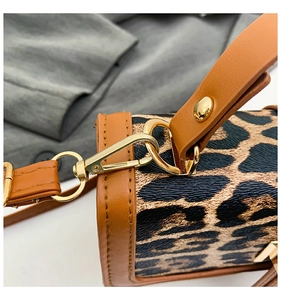 Détail macro du sac à imprimé léopard avec ferrures dorées et finitions en cuir marron