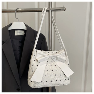 Detail of white seersucker tote bag with large bow and black polka dot embroidery