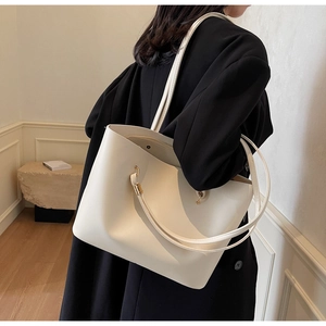Close-up of cream white minimalist tote bag with smooth texture and long shoulder straps