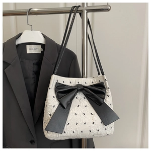 Detail of white quilted tote bag featuring a large black bow and rabbit print on a hanger
