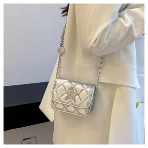 Detail of silver quilted crossbody bag featuring a rhinestone star and metal chain strap