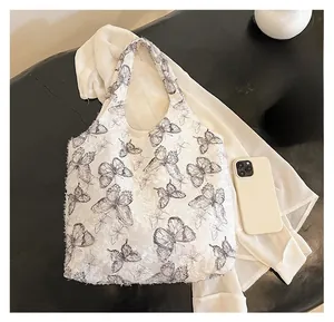 Detailed top view of white lace tote bag with black butterfly print and daily essentials