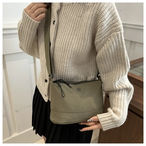 Détail du sac bandoulière en toile vert armée avec logo floral et sangle en nylon