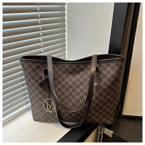 Detail of brown tote bag with repeating M-letter print and metallic M-logo charm