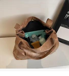 Detail view of spacious brown tote bag interior with magnetic closure and items