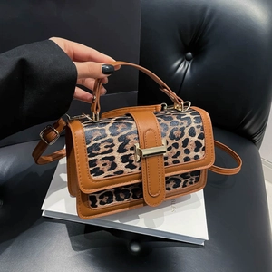 Détail du sac à main léopard avec fermoir magnétique doré et garniture en cuir marron