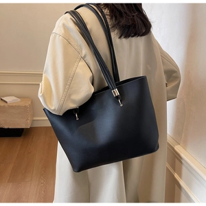 Detail of minimalist black tote bag with long straps and gold metal hardware