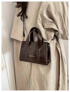 Detailed macro of dark brown glossy wax leather handbag with golden fashion text