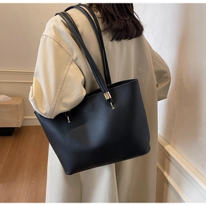 Detail of black tote bag with long slim straps and gold hardware for office