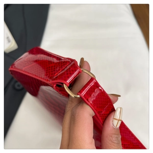 Close-up of bright red snake-patterned leather handbag with gold metal D-ring detail