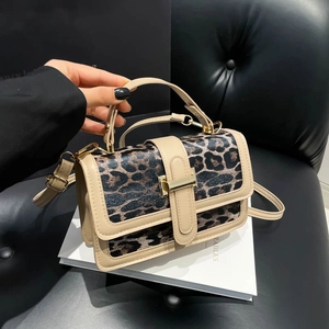 Détail du sac à bandoulière léopard avec bordure beige et boucle en T métallique dorée