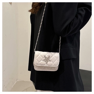 Close-up of white quilted crossbody bag with star-shaped diamond buckle and chain strap