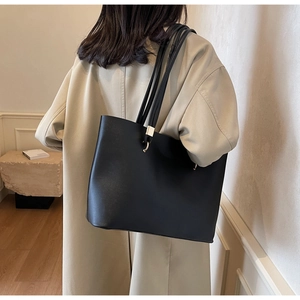 Detail shot of a minimalist black leather tote bag with elegant golden metal buckles