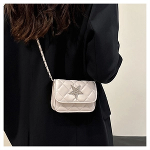 Close-up of a white quilted crossbody bag with a silver rhinestone star and chain strap