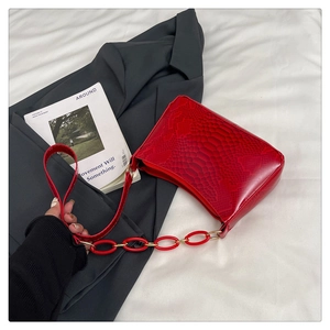 Detail of red snake pattern underarm bag with glossy leather texture and chain strap