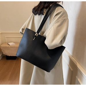 Detail of minimalist black tote bag with multi-strap shoulder design and gold metal accents