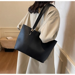 Detail of matte black tote bag with multiple slim straps and gold metallic accents