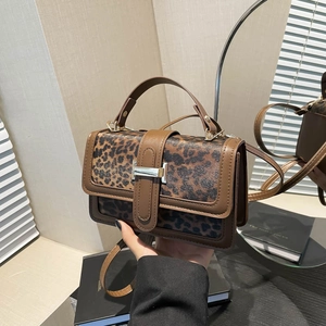 Gros plan d'un sac à main léopard avec boucle en H métallique et finitions en cuir chic