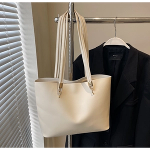 Detailed close-up of cream white tote bag with elegant gold hardware and slim handles
