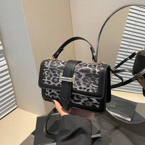 Détail d'un sac bandoulière léopard avec boucle argentée et finitions en cuir noir