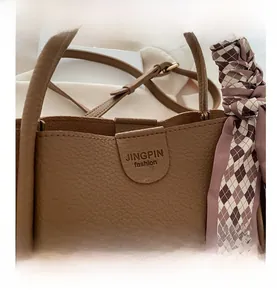 Détail du sac seau en cuir marron à motif litchi avec fermoir magnétique et foulard