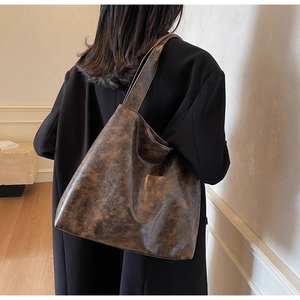 Brown vintage faux leather hobo tote bag with distressed texture on a shoulder model