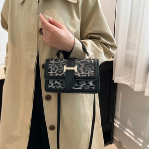 Détail d'un sac à main imprimé léopard avec fermoir doré et bordure en cuir noir