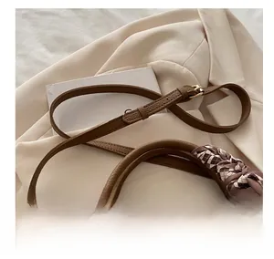 Détail de la texture cuir grainé marron avec foulard en soie enroulé sur la poignée