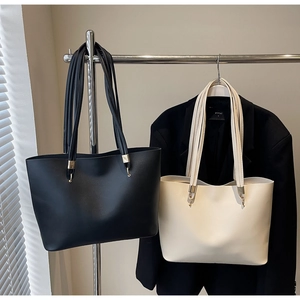 Detail shot of minimalist black and beige tote bags hanging with sleek shoulder straps
