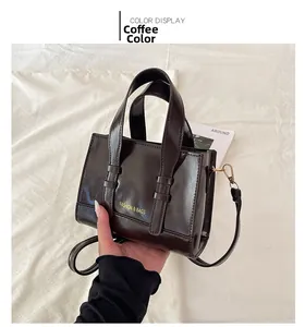 Close-up of small coffee brown leather handbag with gold logo and detachable strap