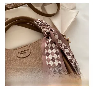 Détail du sac à main en cuir marron avec foulard en soie et gaufrage de la marque