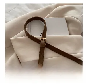 Détail macro de la bandoulière en cuir marron avec sa boucle en métal doré chic
