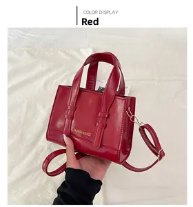 Detail of red wax leather handbag showing fashion lettering and gold metal hardware