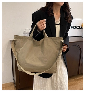 Dettaglio della borsa tote kaki in tela indossata a spalla con grande spazio interno