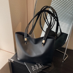 Minimalist black tote bag in matte finish with gold rings and sleek dual shoulder straps