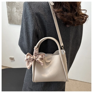 Sac seau en cuir beige avec foulard en soie porté par un mannequin chic