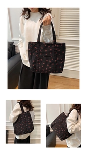 Detail of black corduroy tote bag featuring red strawberry patterns and sturdy shoulder straps