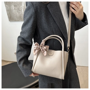 Détail d'un sac seau crème minimaliste avec foulard en soie et bandoulière amovible