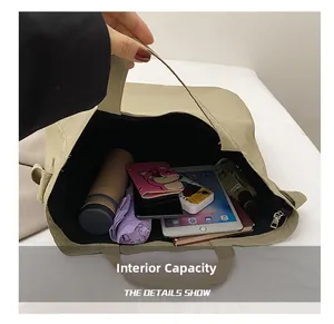 Dettaglio della capienza interna della borsa tote in tela kaki con vari oggetti comuni
