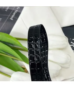 Gros plan d'une bandoulière en similicuir verni noir avec texture embossée motif crocodile