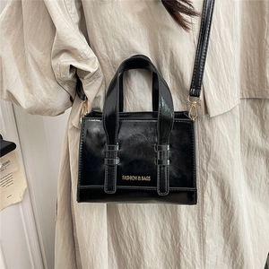 Chic black oil wax leather tote bag with gold lettering and adjustable shoulder strap