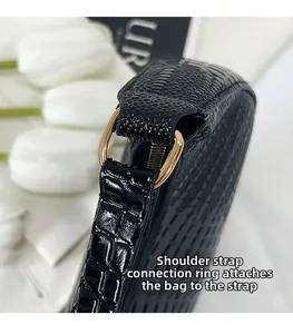 Détail du cuir gaufré crocodile et du connecteur en métal doré sur le sac à bandoulière noir
