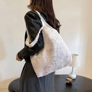Minimalist white textured tote bag with embroidery shown on a model in a cozy interior