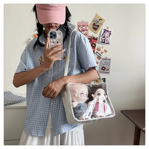 Detail of white ita bag with transparent window showcasing cute plush toys inside