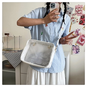 Lifestyle shot of white crossbody ita bag with large transparent window and gold metal buckle
