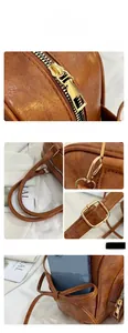 Close-up of litchi grain leather texture with gold metal zipper and bow detail on brown bag