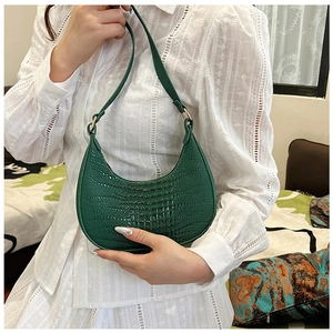 Sac hobo vert à texture crocodile porté par un mannequin en chemisier de dentelle
