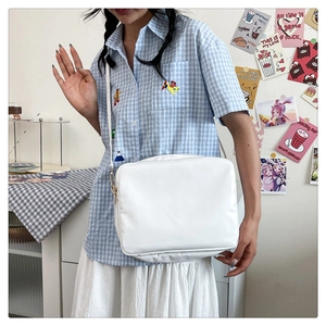 Detailed view of the white minimalist rectangular shoulder bag with golden buckles on a model