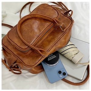 Macro view of brown vintage pleated PU leather bag with multi-zipper pocket detail