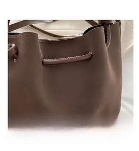 Detailed macro view of dark brown faux suede texture and stitching on the bucket bag